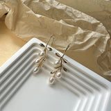 Gold hook earrings featuring tiered drop leaves adorned with three pearls, adding a touch of elegance and nature-inspired charm