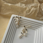 Gold hook earrings featuring tiered drop leaves adorned with three pearls, adding a touch of elegance and nature-inspired charm