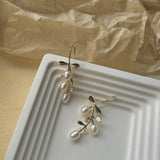 Gold hook earrings featuring tiered drop leaves adorned with three pearls, adding a touch of elegance and nature-inspired charm