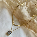 18k gold layered necklace featuring a diamond, designed to be waterproof and hypoallergenic for everyday wear.