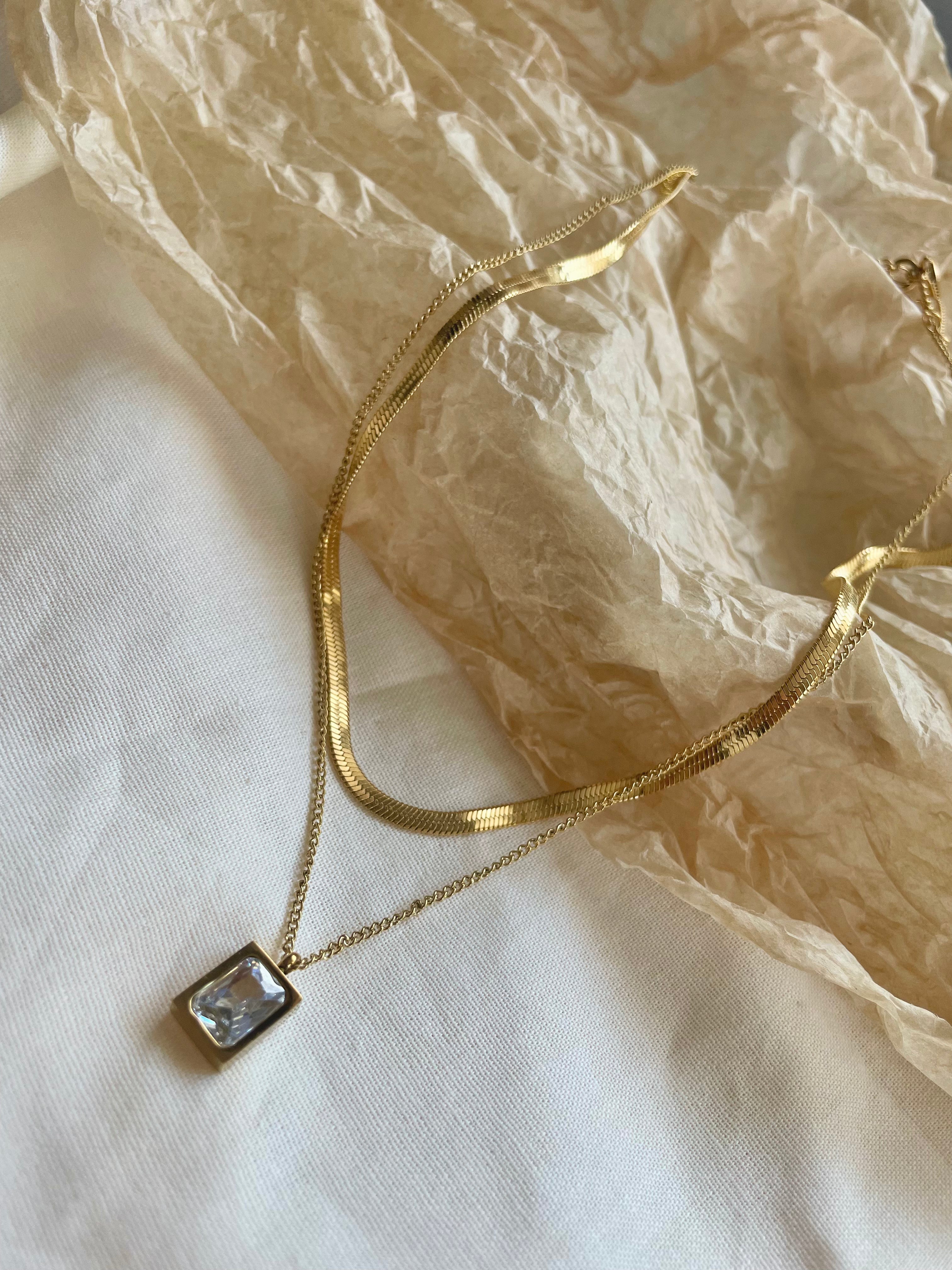 18k gold layered necklace featuring a diamond, designed to be waterproof and hypoallergenic for everyday wear.