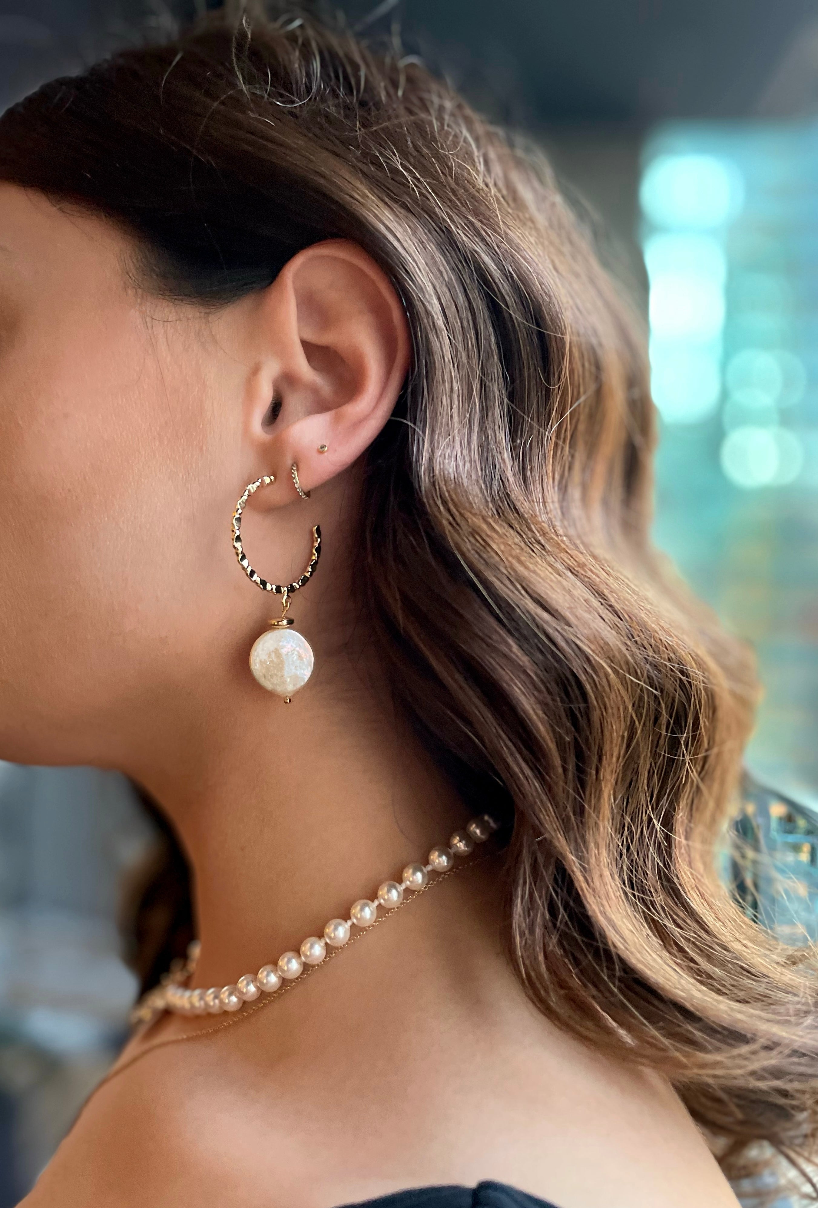 model wearing 18k gold textured hoop earrings featuring a coin pearl