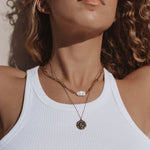 Model wearing 18k gold layered necklace with a pearl and roman coin. Waterproof and tarnish-resistant design.