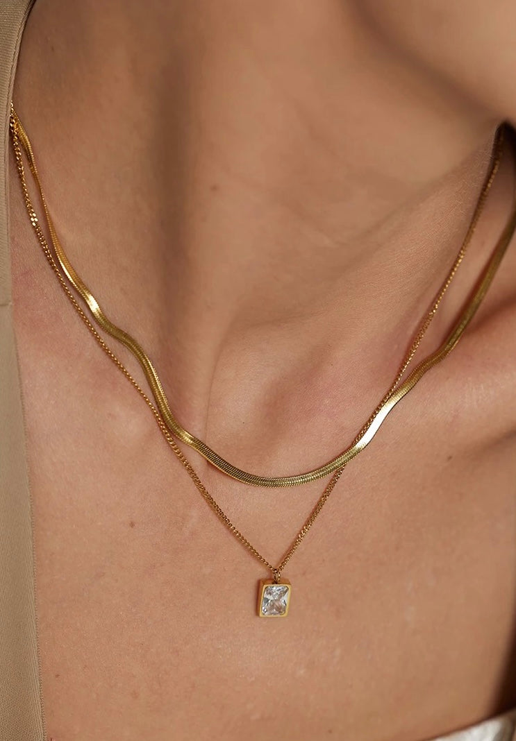 18k gold layered necklace featuring a diamond, designed to be waterproof and hypoallergenic for everyday wear.