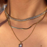 model wearing 18k gold layered necklace featuring a diamond, designed to be waterproof and hypoallergenic for everyday wear.