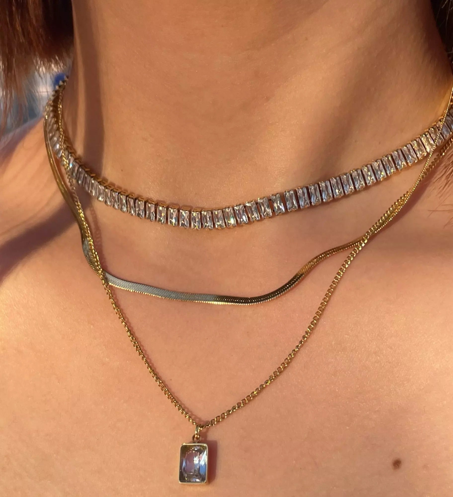 model wearing 18k gold layered necklace featuring a diamond, designed to be waterproof and hypoallergenic for everyday wear.