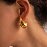 Model wearing 18k gold teardrop earrings embellished with cubic zirconia, featuring a statement design that is waterproof and hypoallergenic