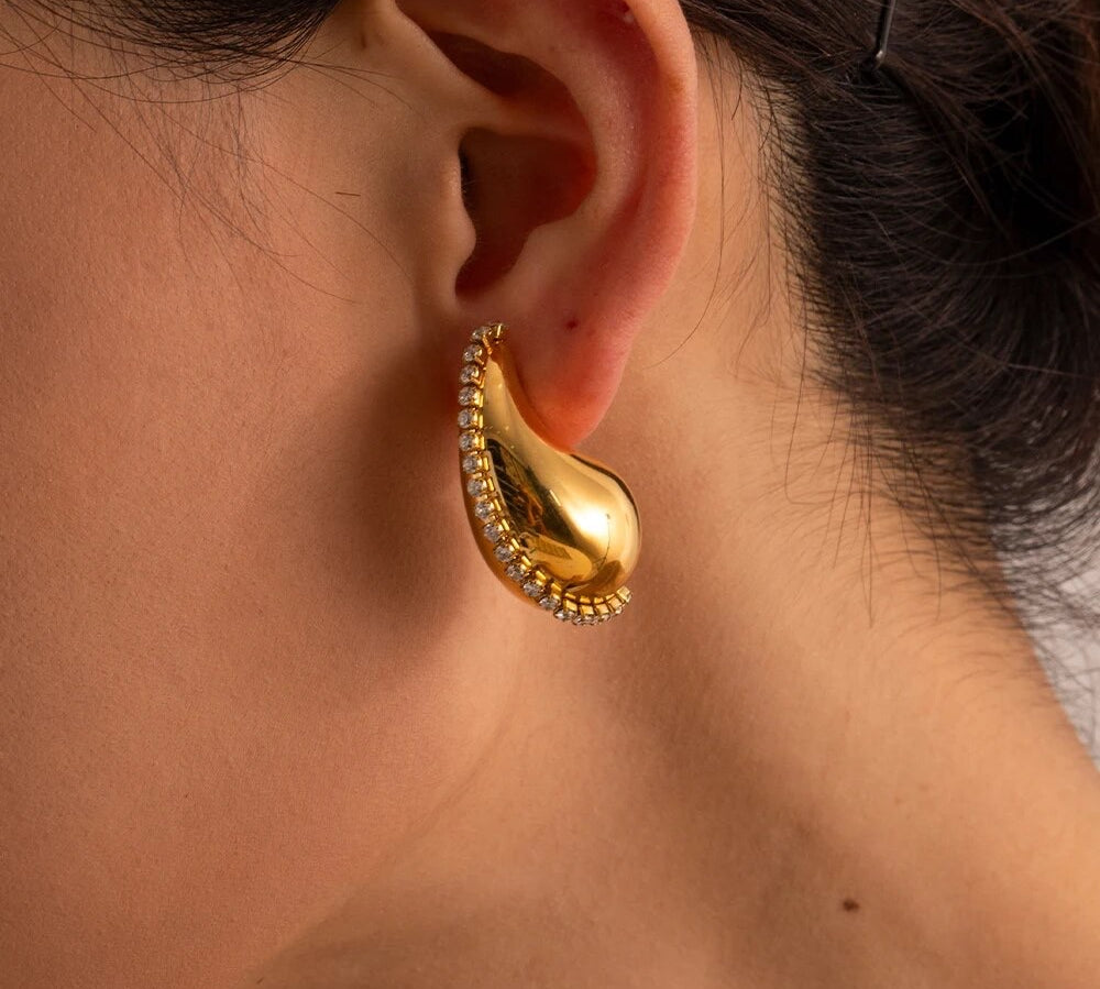 Model wearing 18k gold teardrop earrings embellished with cubic zirconia, featuring a statement design that is waterproof and hypoallergenic