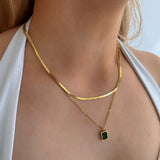 model wearing 18k gold layered necklace featuring a emerald colour designed to be waterproof and hypoallergenic for everyday wear.