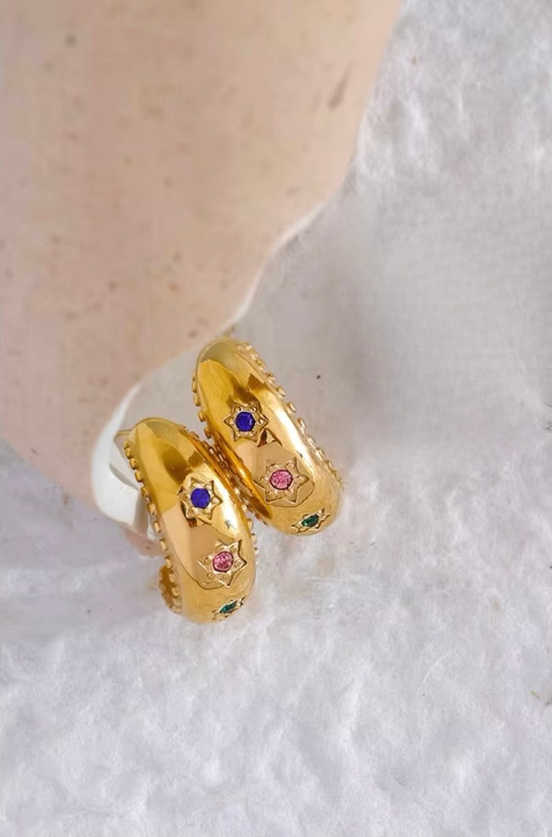 Small hoop earrings with three stars adorned with multi-coloured stones, featuring scalloped edging, designed to be waterproof and hypoallergenic