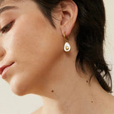 Model wearing 18k gold avocado earrings with a mother of pearl inner, designed to be hypoallergenic and tarnish-resistant for lasting wear