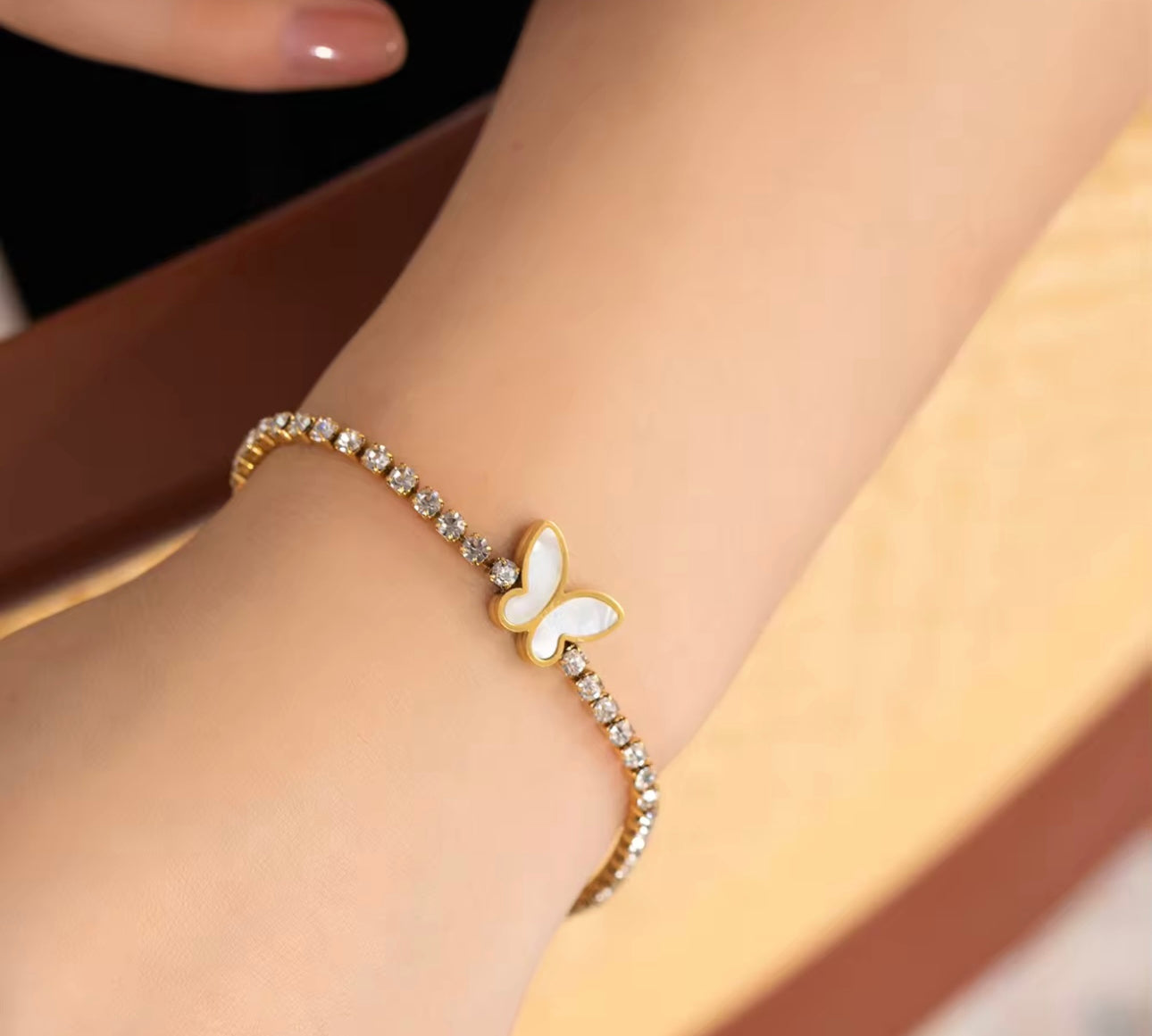 Model wearing 18k gold tennis bracelet featuring a butterfly and flower design with mother of pearl and high-quality cubic zirconia, crafted to be tarnish-resistant for enduring elegance