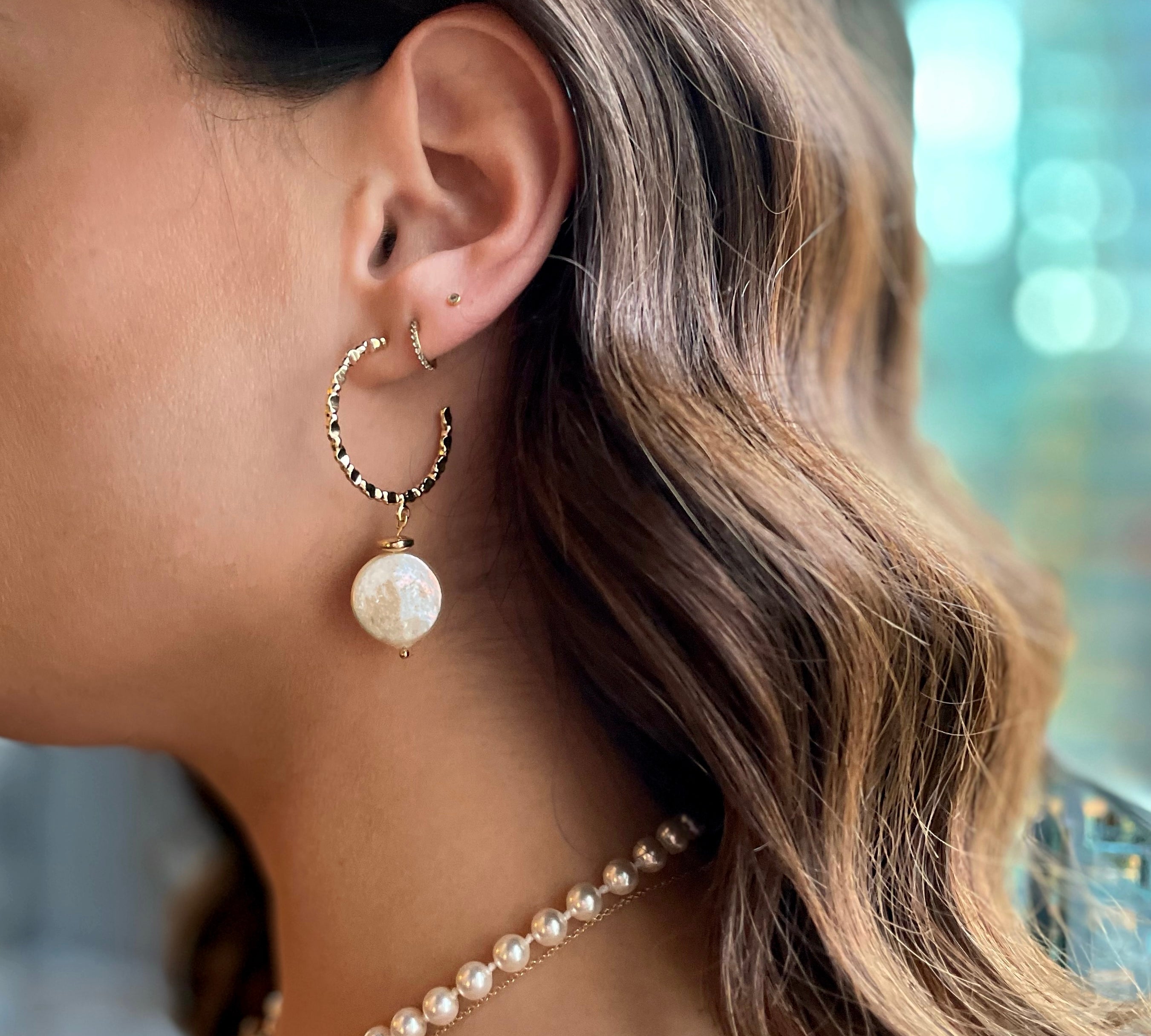 model wearing 18k gold textured hoop earrings featuring a coin pearl