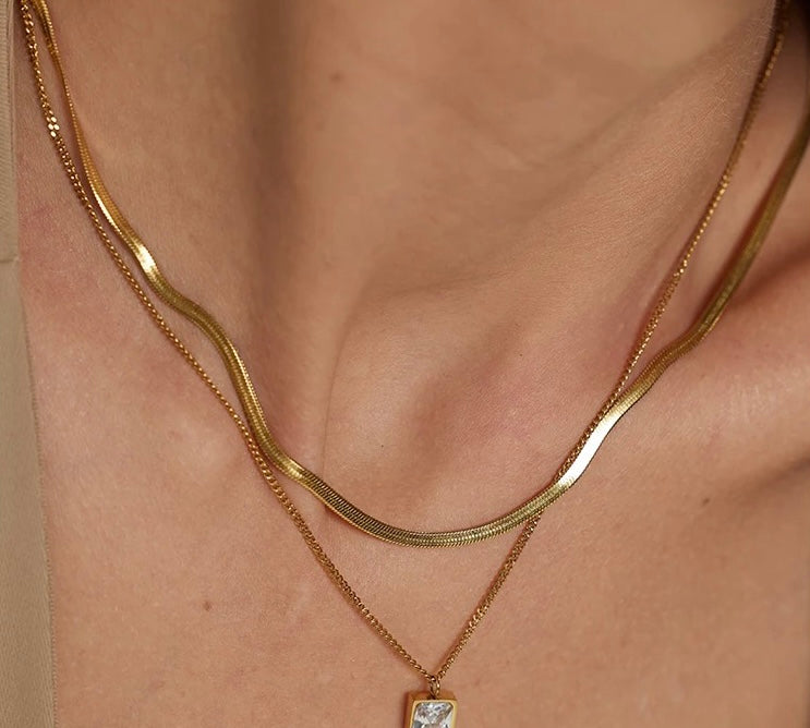 18k gold layered necklace featuring a diamond, designed to be waterproof and hypoallergenic for everyday wear.